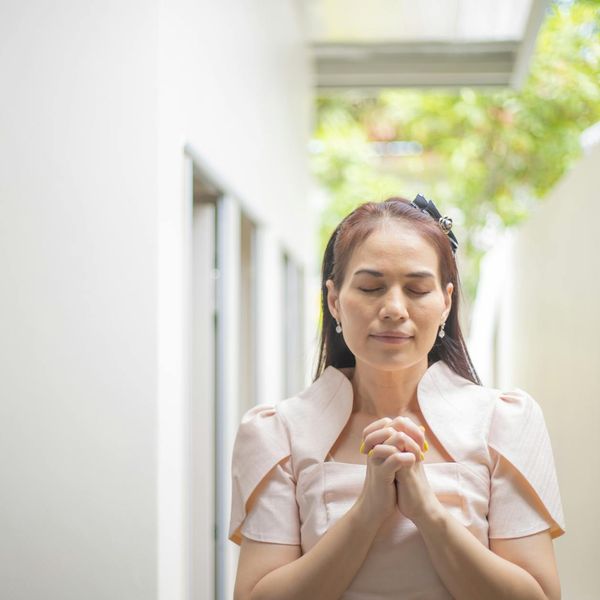 Person meditating with a calm expression against a light background.
