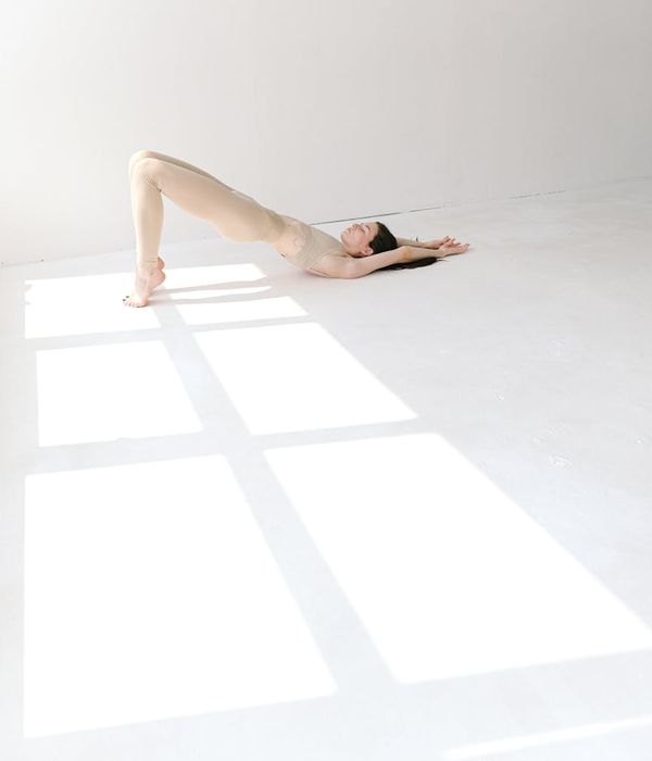 Woman in a calming stretching pose in a bright studio.